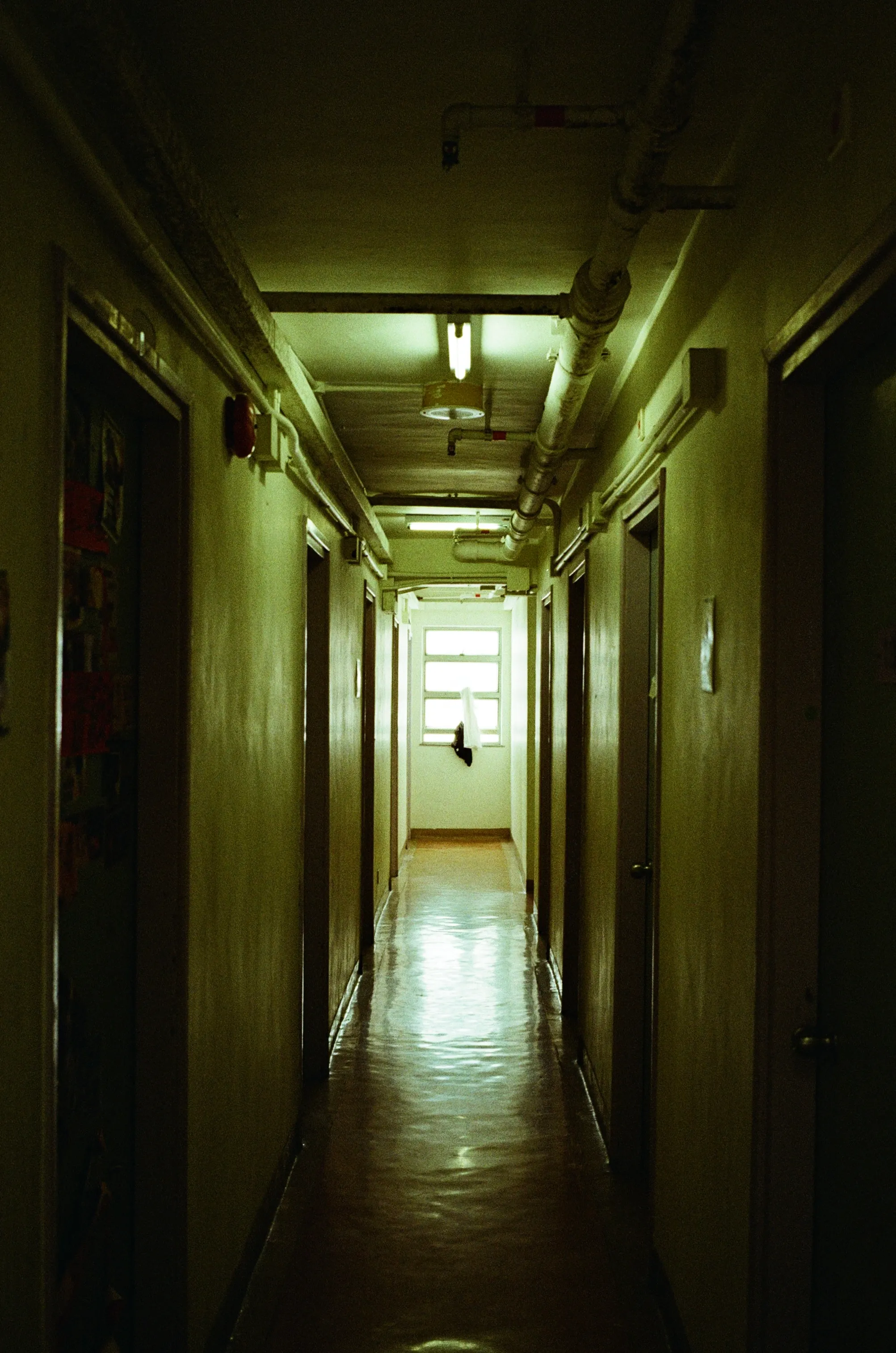 Dim apartment corridor lit by a bright window at the far end