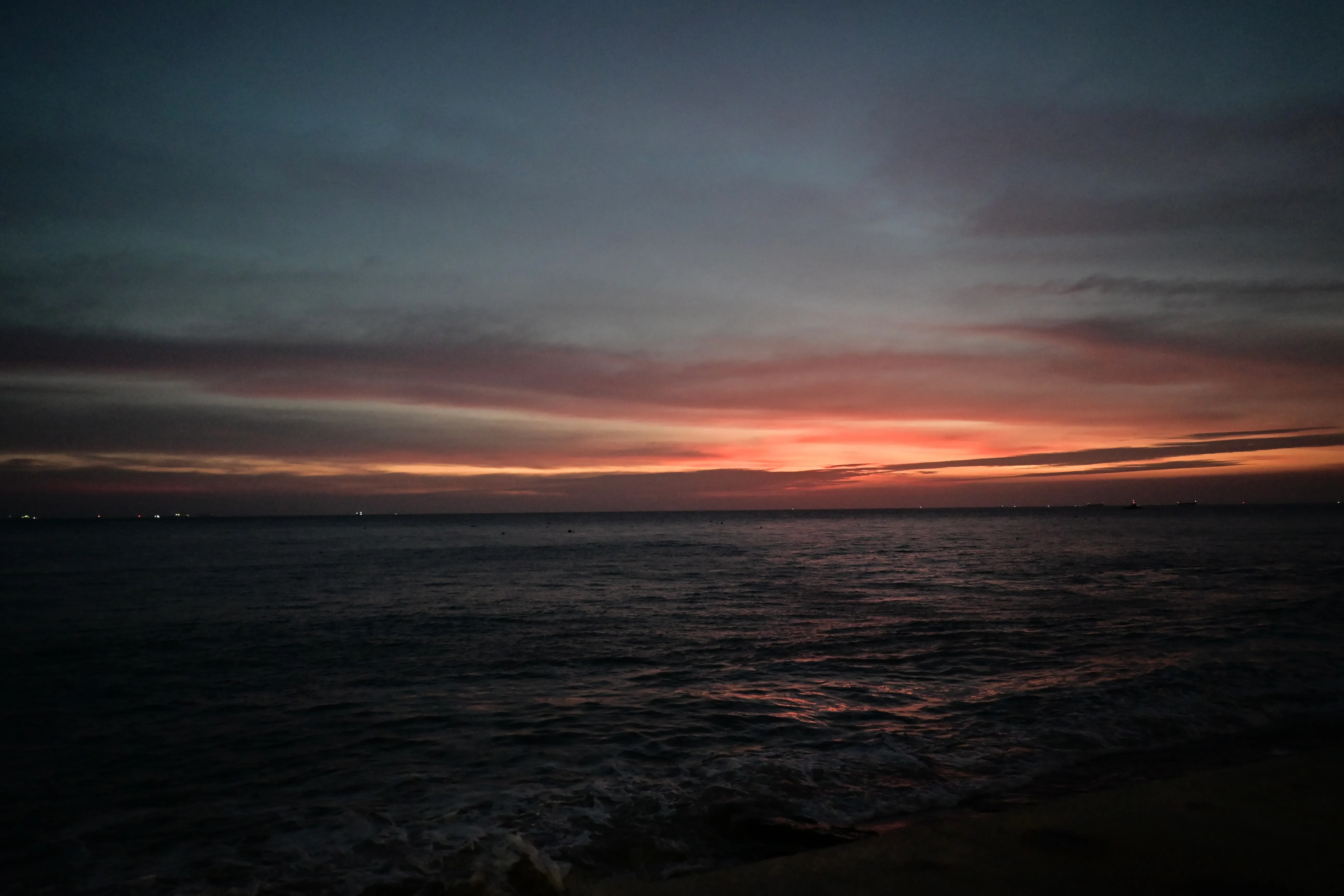 Dark sea at dusk with a band of orange on the horizon