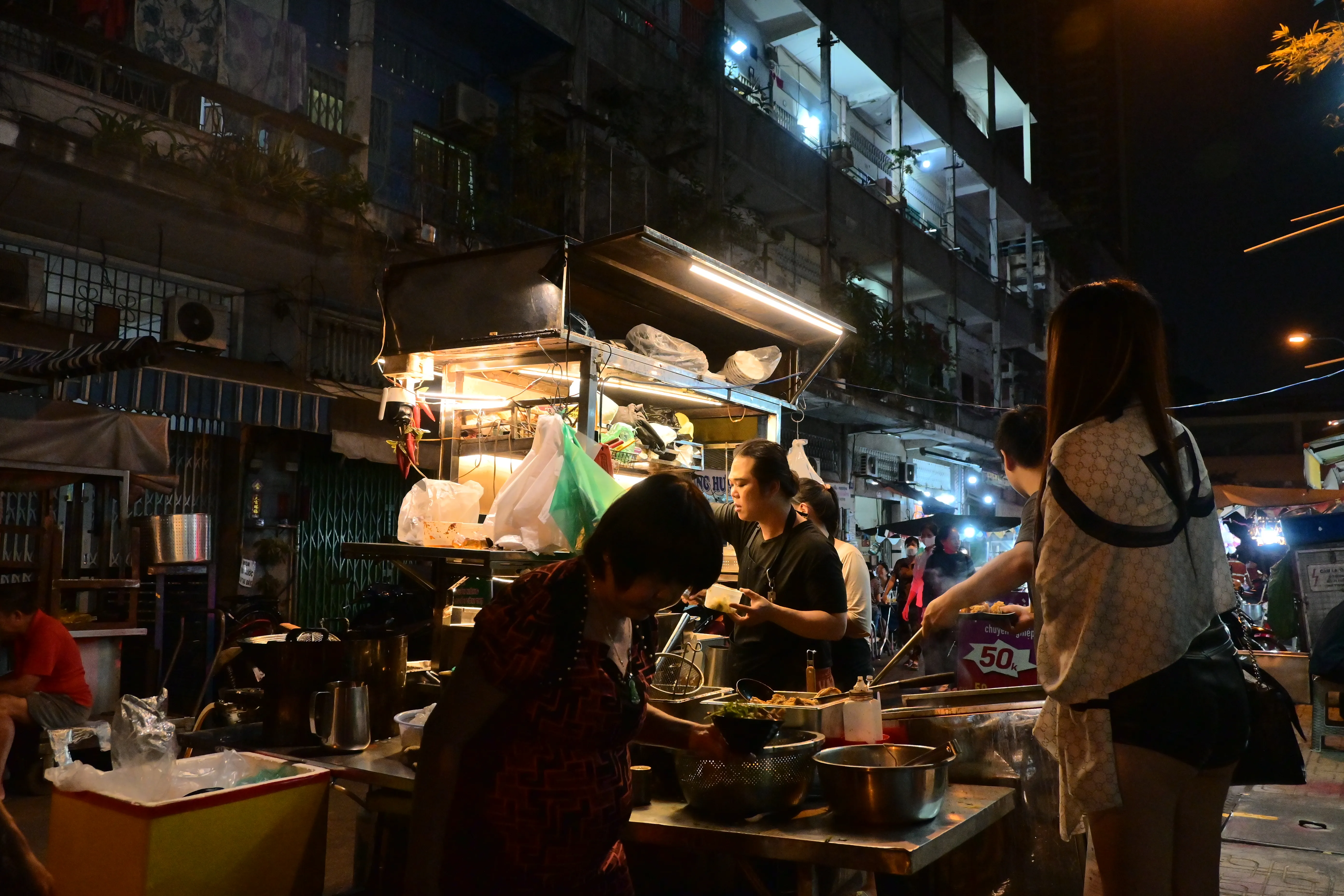 Street food stall glowing at night in front of an old apartment block